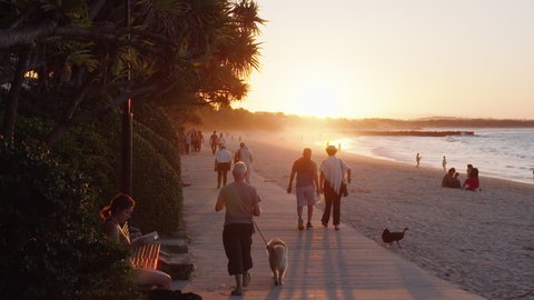 People walking along the boardwalk at Noosa Beach at sunset - Noosa - Queensland - Australia - May 26, 2021.