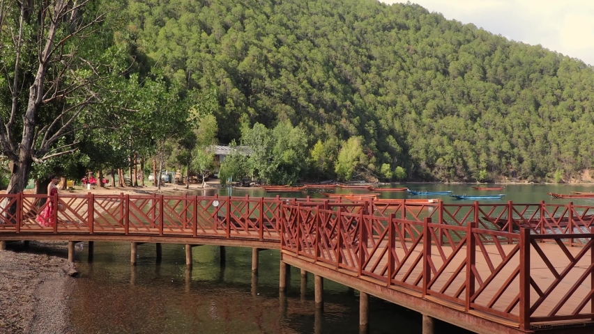 A woman walks on a wooden bridge near the shores of Lugu Lake in Lijiang, Yunnan Province, China