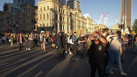 BRISBANE, QUEENSLAND, AUSTRALIA. JUNE 06 2020. Moving through the city, Black Lives Matter protestors in the sun, slow motion.