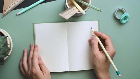 Women's hands ready to write in the empty notebook on the pastel blue background. Place for text. Minimalistic working table for creative job or planning