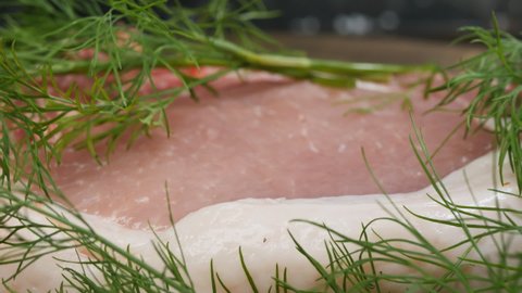 fresh pork pink meat with fat on the edge. With fresh green dill sprigs. The entrecote rotates. Extreme close-up.