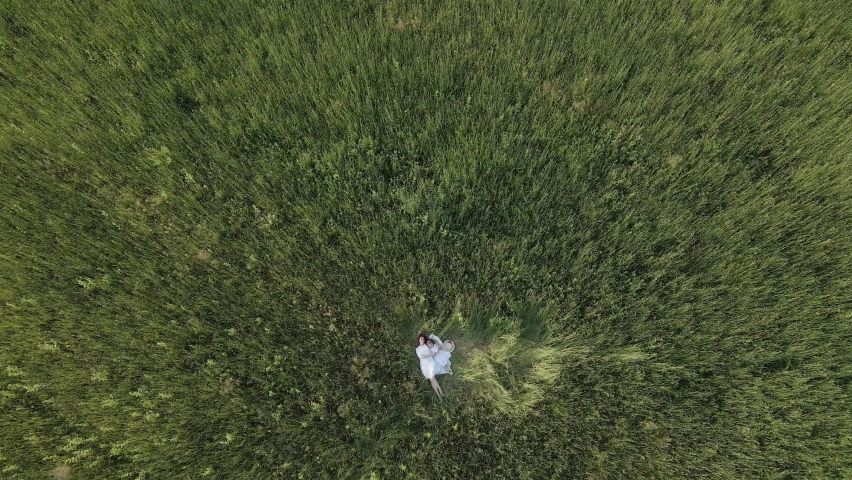 mom and daughter in white clothes dresses lie on a field