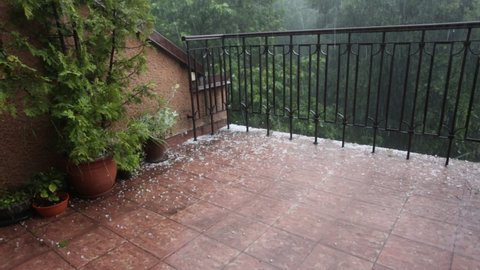 Cracow, Malopolska, Poland - 07.09.25.2021: Hailstones falling on terrace and plants during the hailstorm. Extreme wheather phenomena such as hailstorms are effect of global warming.