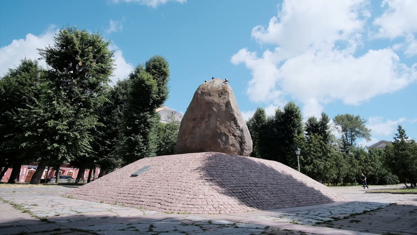 A big unusual stone on a moss-covered rocky plain against a cloudy sky