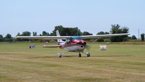Ferrara Italy JUNE, 27, 2021 Small private light aircraft in red and white livery taxiing on a grass airfield. Cessna C182P Skylane is also used for pilots training.