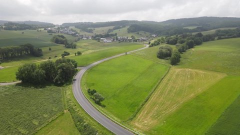 German Eifel twisty road through the hills in a sunny grassland in the summer.