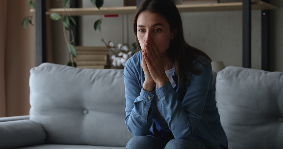 Unhappy frowning stressed young 20s woman worrying about wrong decision or feeling jealous alone at home, sitting on sofa, regretting mistakes, thinking of health problems or relationship troubles. Royalty-Free Stock Footage #1075713101