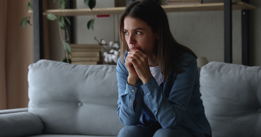 Unhappy frowning stressed young 20s woman worrying about wrong decision or feeling jealous alone at home, sitting on sofa, regretting mistakes, thinking of health problems or relationship troubles. | Shutterstock HD Video #1075713101