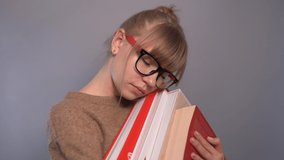 Tired nerd, attractive university or college blonde caucasian student girl wearing eyeglasses and beige sweater holding stack of books in hands. Education or knowledge concept. High quality 4k video