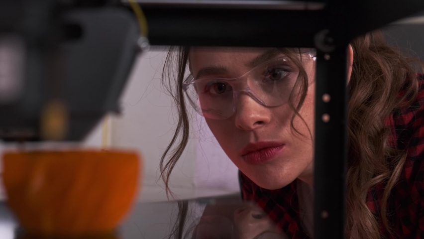 Designer student using a 3D printer in college. Female designer print prototype on 3D printer