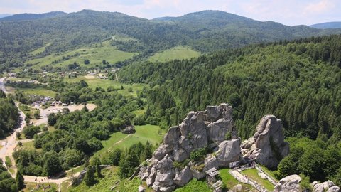 Aerial drone footage flying near rocks of famous Tustan fortress. Ukrainian medieval cliff-side monument in national park. Rock complex of Tustan is popular tourist landmark in Carpathians mountains