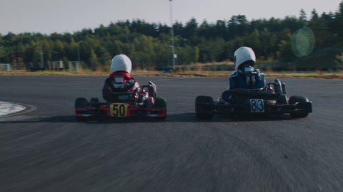 TRACKING Two teenagers pro racers driving their karts on a race track. Shot with 2x anamorphic lens