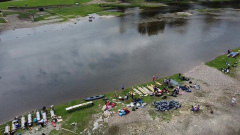 Republic of Bashkortostan, Starosubkhangulovo village. A group of tourists on the banks of the Belaya River collect catamarans for rafting. A healthy and active hiking lifestyle.