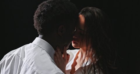 Romantic scene, moment before kissing, love game, two lovers standing in twilight, flirtation of attractive brunette with dark skinned man, sensual touch on the neck, deep looks, smiles