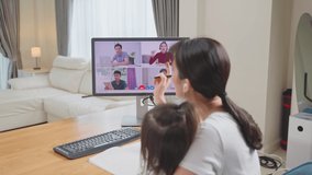 Asian Businesswoman freelance working at home with daughter on hands. Office worker woman mother talk to colleague team on virtual video call conference meeting online due to Covid19 lockdown in house