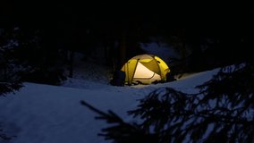 Yellow iluminated tent in winter forest At Night, silhouette of a people in a tent. Active recreation and travel concept. - Powered by Shutterstock - Get 15% off with code: PIKWIZARD15