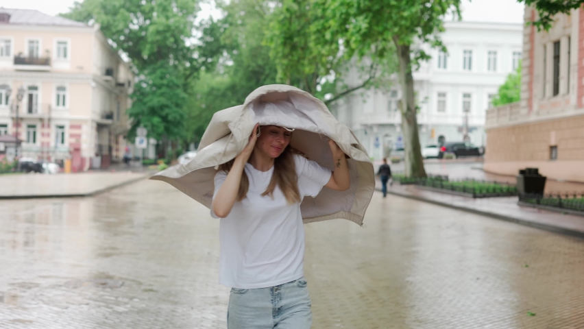Female under rain drops cover head with coat, slow motion Royalty-Free Stock Footage #1075738769