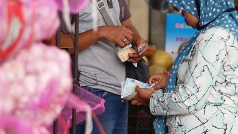 Tarakan, Indonesia, July, 12 2021: An Indonesian man paying with cash money in tradtional market. Indonesian man paying on traditional market using cash money