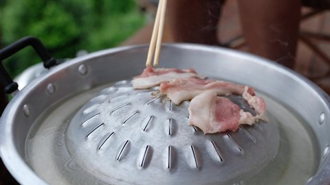 People cooking and eating Moo Kata, Thai barbecue grill pork on circle hot pan