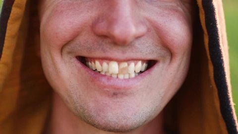Yellow damaged tooth of smiling Caucasian man in the hood close-up. Focus on the teeth, open mouth. Dental problems, dead teeth, enamel whitening, aesthetic restoration. Natural enamel, body positive