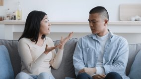 Asian Couple Having Quarrel Sitting On Couch At Home. Young Chinese Family Has Conflict And Marital Problems. Misunderstanding In Relationship Concept. Zoom In