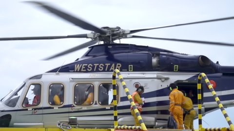 KELANTAN, MALAYSIA - OCT 22nd 2021: Slow motion footage of unidentified offshore workers unloading luggages from Weststar AW139 helicopter cargo area upon arrived.