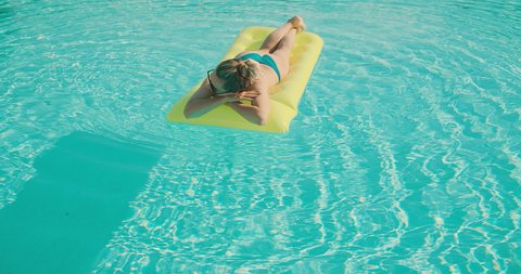 Woman swim in the pool, sunbathes, swimming on the air mattress in hot summer day. Relax, Travel, Holidays, Freedom concept. 4K slow motion