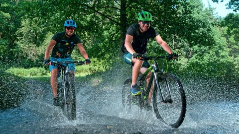 Super Slow Motion Shot of Two Men on Mountain Bike Crossing The River at 1000 fps.