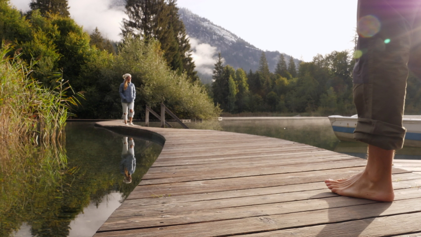 Young couple contemplating stunning alpine lake from wooden dock. Romantic getaway concept