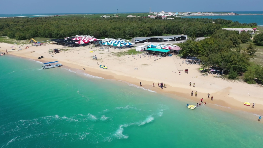 Aerial view of outdoor enthusiasts enjoying jet skiing, banana boat riding and other water sports at a beautiful beach on Jibei Island, a famous tourist destination in Baisha Township, Penghu, Taiwan Royalty-Free Stock Footage #1075756784