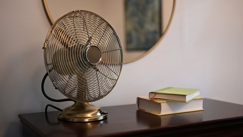 Oscillating vintage fan on dresser with books