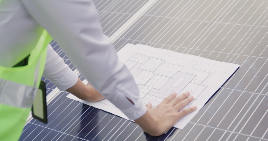 Engineer open blueprint of solar farm project on solar cells panel summary report, technology and green ecology energy system concept. | Shutterstock HD Video #1075759274