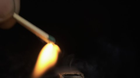 Slow motion. Ignition of a match by rubbing against a matchbox. Man blowing on a burning match and extinguishing the flame. Close-up