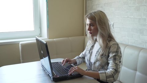 Woman works behind laptop in kitchen