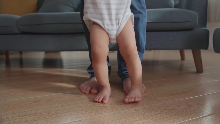 Close Up Father Holding And Helping His Little Baby Learning To Walk On Floor At Home
 | Shutterstock HD Video #1075765802