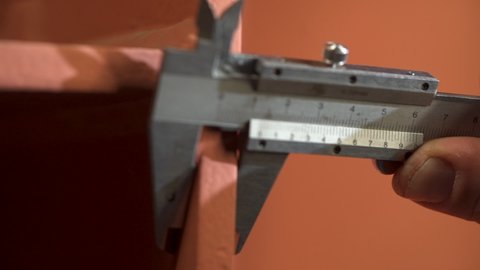 Measuring metal piece with vernier caliper. Worker conducts defect diagnosis