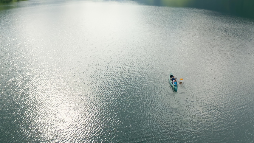 Aerial shot of a canoe in a lake, beautiful view of mountains and hills illuminated by the sun