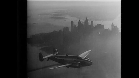 CIRCA 1960s - An airplane flies past the Empire State Building and other skyscrapers in New York City.