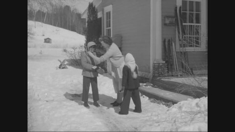 CIRCA 1950 - Children are dressed warmly to walk to school in the snow in Pittsford, Vermont, and they warm up by the furnace.