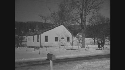 CIRCA 1950 - A couple arrives at the schoolhouse where they work in Pittsford, Vermont, and the husband turns on the furnace.