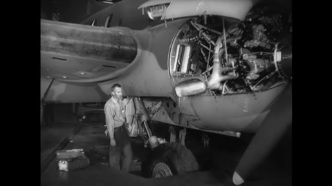 CIRCA 1940s - Men assess landing gear on a C-46 In a factory.