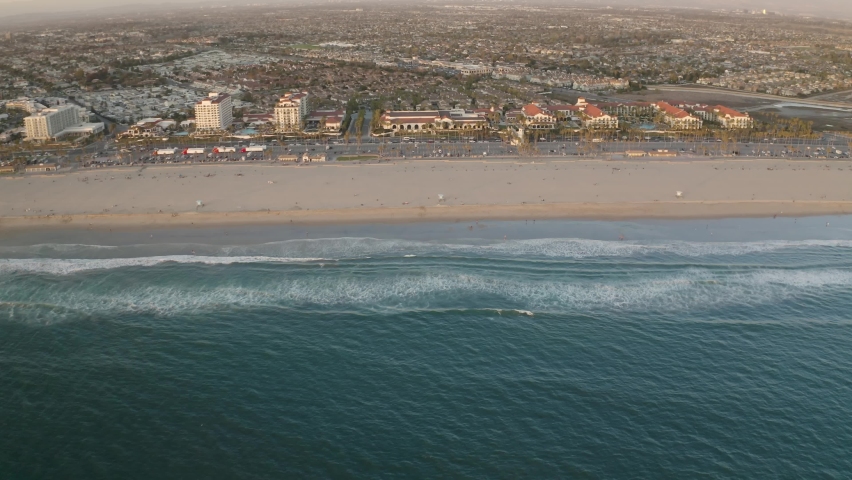Aerial view of ocean waves and beach at sunset in Huntington Beach, California - 4K Drone