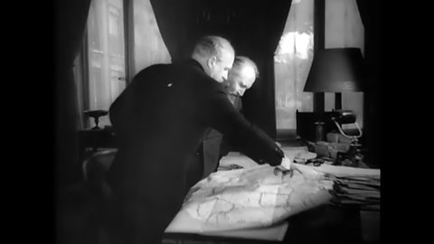 CIRCA 1940s - Two French statesmen look over a map together.