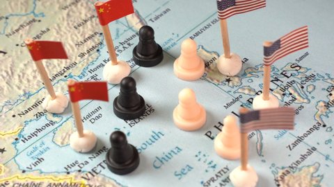 Chinese and U.S. flags with chess pieces symbolizing the conflict and control of the South China Sea.