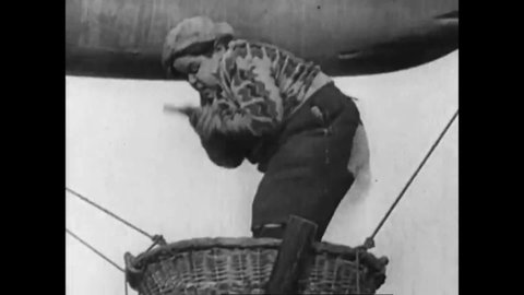 CIRCA 1920s - A 1920s silent comedy sketch of kids playing a prank on a chubby boy sitting in a basket held up by a mini zeppelin.