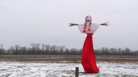 Zaporizhzhia, Ukraine - March 13, 2021: Slavic holiday Maslenitsa. Pagan doll against the gray sky. Idol for the holiday. Pancake Festival. The wind blows the ribbons