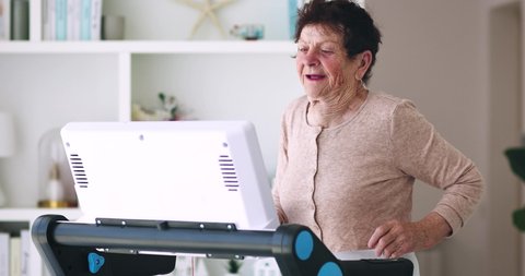 cheerful mature woman running on treadmill at home, sporty lifestyle, 84 years old lady