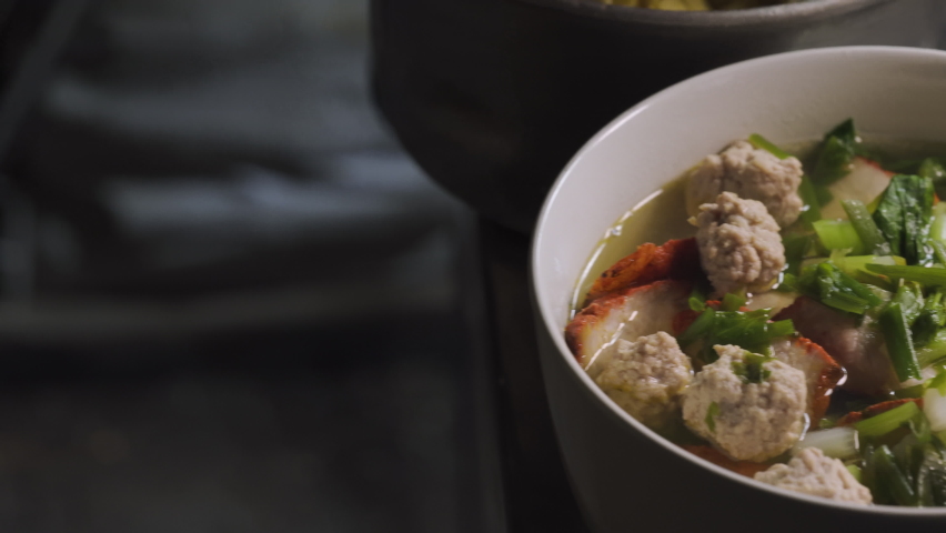 Finish bowl of chinese noodle full of ingredients. bok choy, red pork, pork and dumpling. Noodle making.