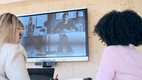 Video of multiethnic entrepreneurs doing a working video call with their colleagues in TV at coworking place.