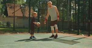 Professional american basketball player instructor train little sports boy outdoor on basketball court